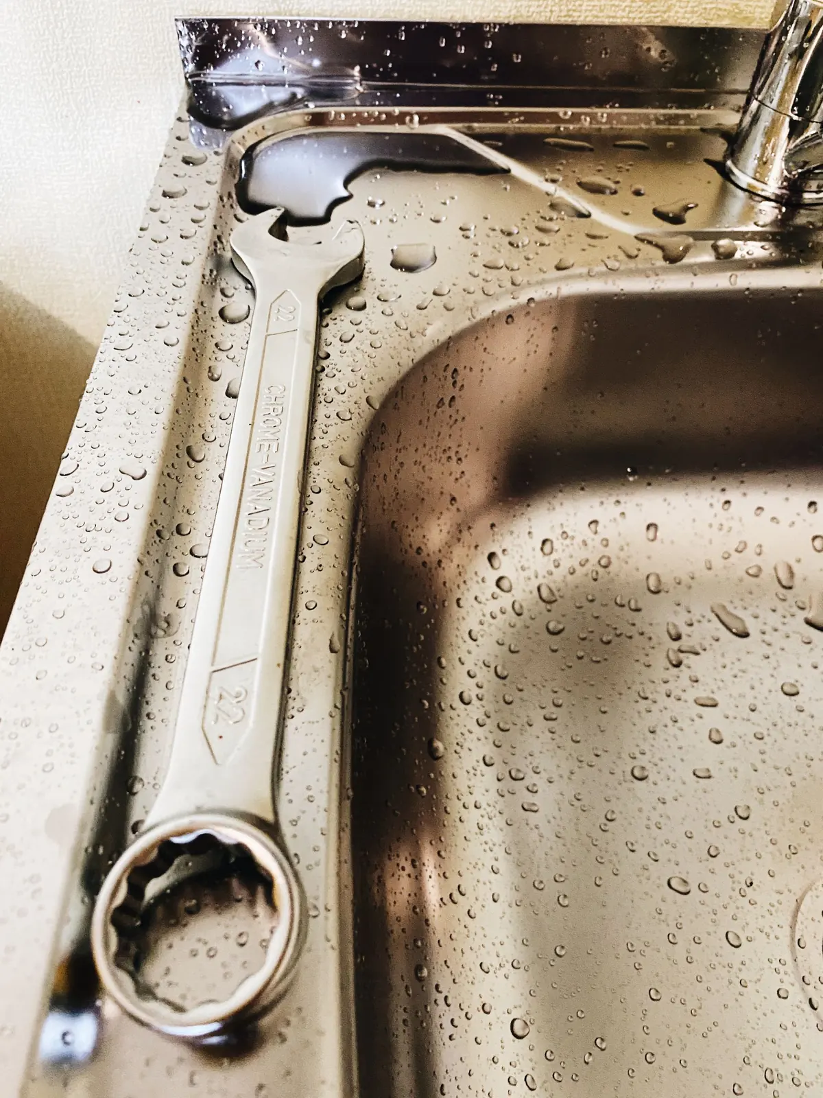 Steel spanner beside a wet stainless-steel sink